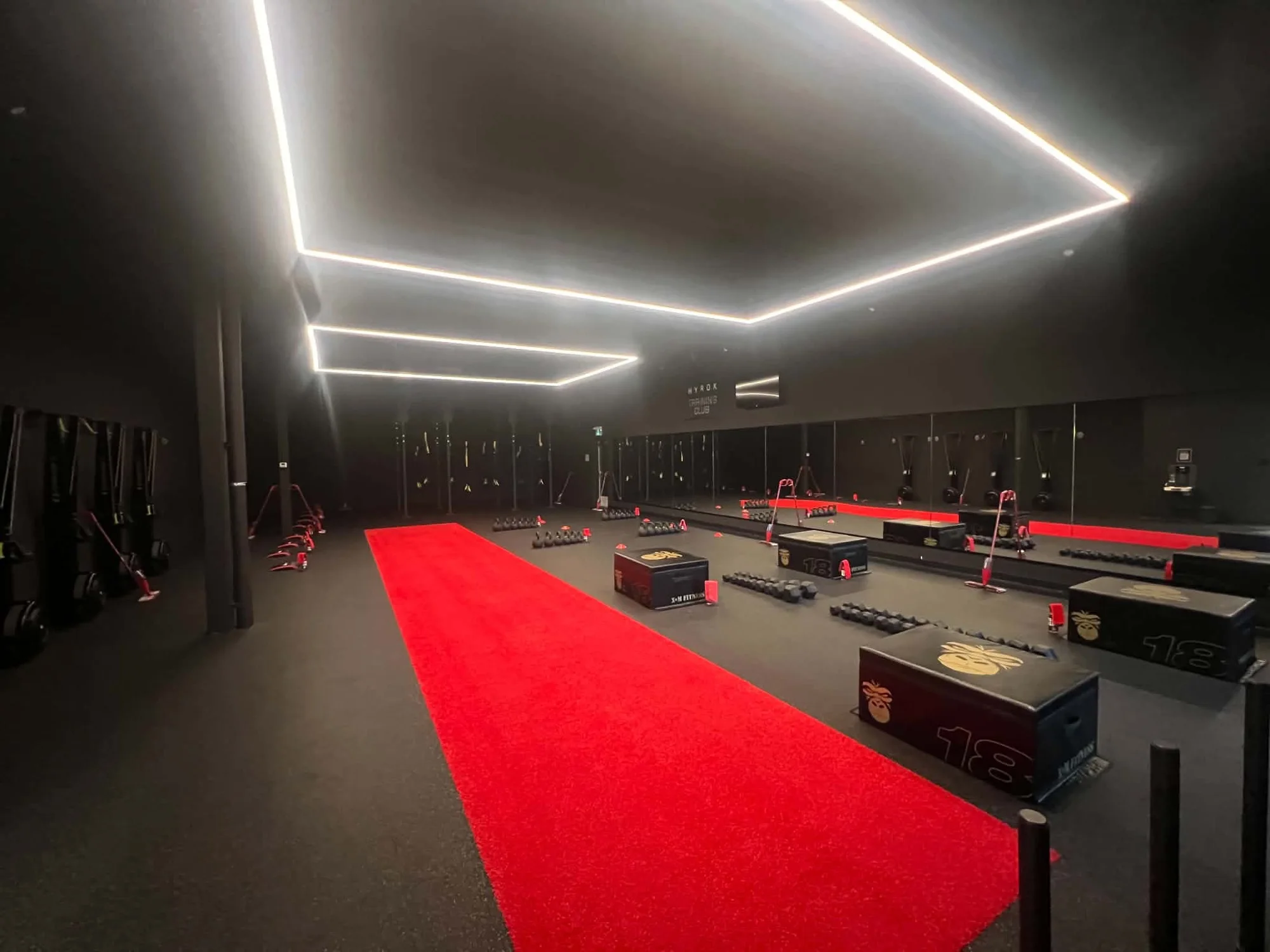 Salle d’entraînement, tapis rouge et cadres lumineux au plafond